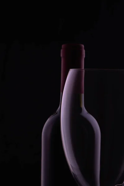 Rotweinglas Und Eine Weinflasche Mit Reflexionen Auf Schwarzem Hintergrund — Stockfoto