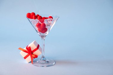 Kırmızı kalpli bir bardak şeker, buz ve mavi bir arkaplan hediye paketi. Aşk zamanı. Sevgililer günü, yıldönümü ya da düğün kutlaması konsepti. Boşluğu kopyala.
