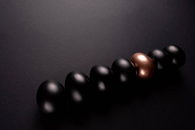 Bir altın yumurta ve siyah yumurta fotokopi alanı ile siyah arka planda yatar.