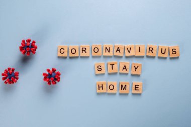 Mavi arka planda ahşap harflerden ve covid-19 virüsünün modellerinden oluşan güvenli bir konsept.