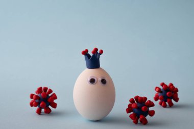 Korona giyen yumurta ve mavi arka planda covid-19 virüsü modelleri. Salgın koronavirüs COVID-19 konsepti. - Virüs salgını.