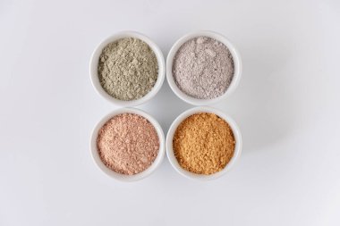 Beyaz arkaplanda farklı kozmetik çamur tozları.