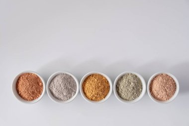 Beyaz arkaplanda farklı kozmetik çamur tozları.