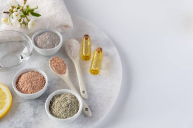 Beyaz arka planda farklı kozmetik çamur tozları. Ev yapımı yüz ve vücut maskesi veya fırça ve çiçek açan kiraz filizleri için malzemeler. Spa ve vücut bakımı kavramı.