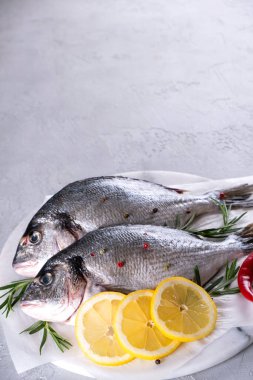 Gri arka planda lezzetli taze balık. Aromatik otlu, baharatlı ve limonlu balık - sağlıklı yiyecek, diyet veya aşçılık konsepti 