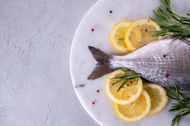 Taze çiğ Dorado kuyruğu ya da mermer tahtada baharatlar, otlar, limon ve tuzlu deniz kepeği balığı. Üst görünüm