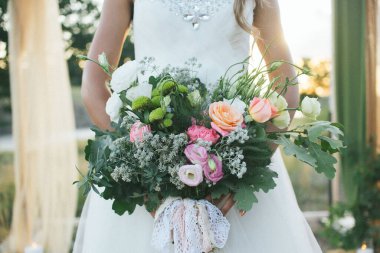 Gelin, törende güzel ve görkemli düğün buketini tutuyor.