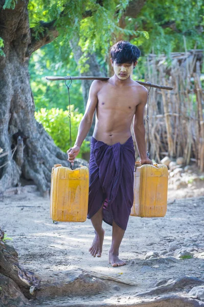 Birman plastik kova taşıyan çiftçi su — Stok fotoğraf