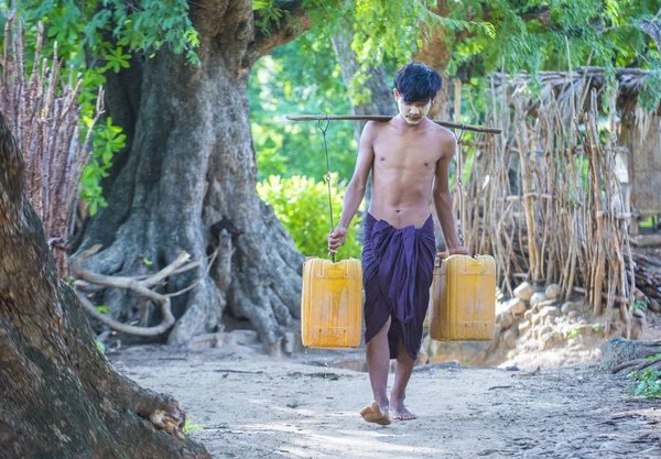 Birman plastik kova taşıyan çiftçi su — Stok fotoğraf