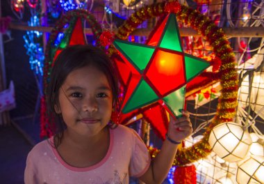 Manila, Filipinler - 14 Aralık 2019 'da Las Pinas, Filipinler' de bir Noel pazarında fener tutan Filipinli bir kız
