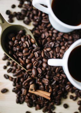 İki fincan kahve kahve çekirdekleri ile ahşap bir masa üzerinde