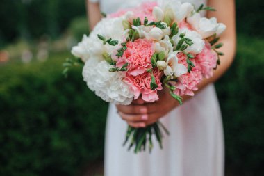 yeşil bir bahçede duran ve bir düğün buket tutan bir elbise içinde gelin 