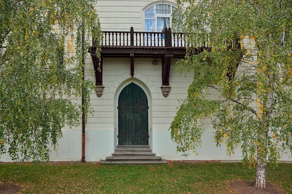 Puerta vieja verde con balcón y ventana de madera y abedul verde — Foto de Stock