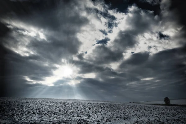 Schneefeld mit bewölktem Himmel und Sonnenstrahlen, Tschechien — Stockfoto