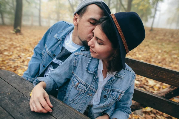 Happy couple sitting on bench and kissing in park