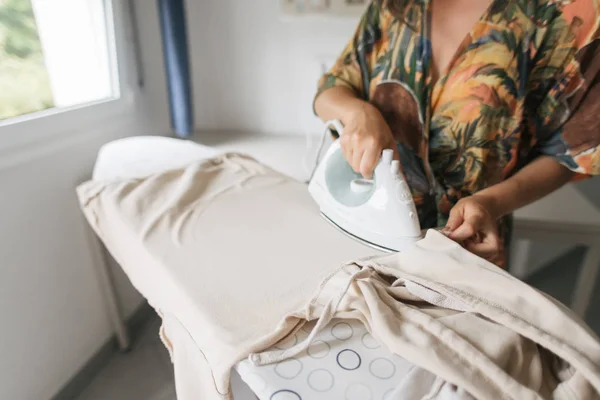 Woman irons clothes with iron — Stock Photo, Image