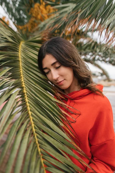 Fille dans un pull rouge se tient près d'un palmier — Photo