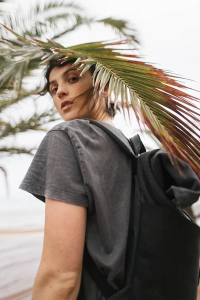 Girl in a red sweater stands near a palm tree — Stock Photo, Image