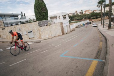 Bisikletçi atlet deniz kenarında yolda gidiyor.