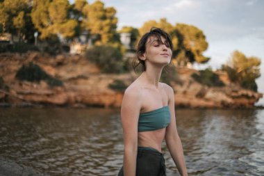 Kadın kumsalda dururken elini kaldırdı.