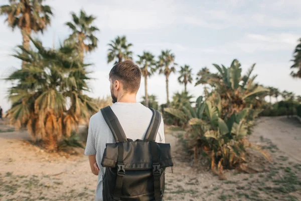 Tipo con mochila viaja de pie cerca de palmeras —  Fotos de Stock