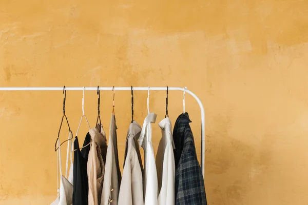 wardrobe, hanger with clothes on yellow background ,pastel color clothes, female clothes on open clothes rail