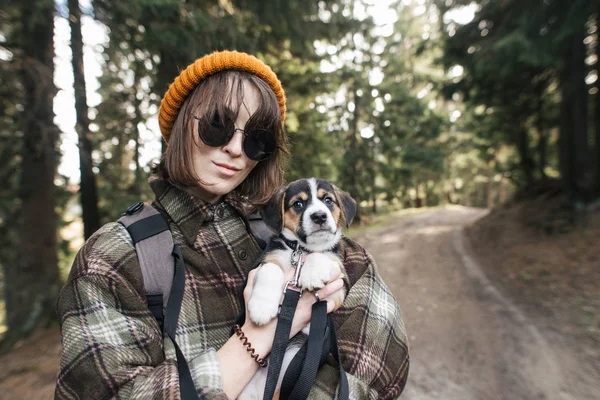 Hiking with dog, girl holding a puppy in her arms in the mountains in forest — Stock Photo, Image
