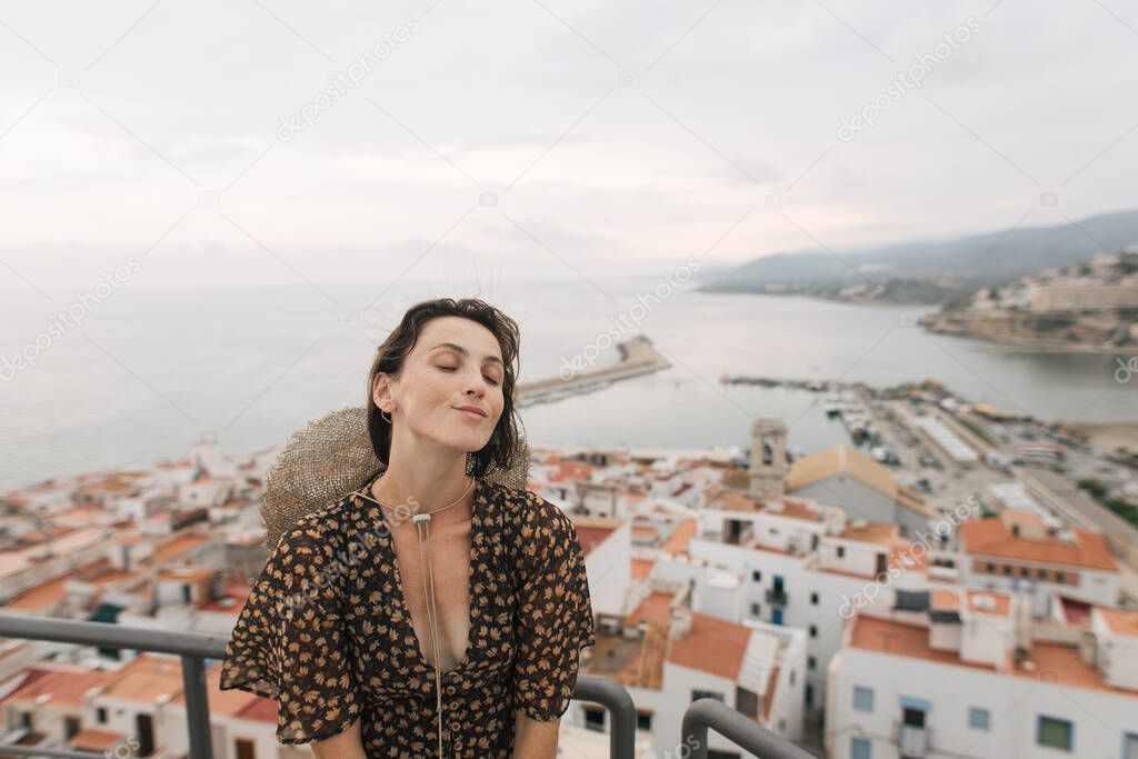 young female traveler stands on top of castle, city view, Peniscola Spain