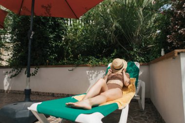 Genç bir kadın havuz kenarında dinleniyor.