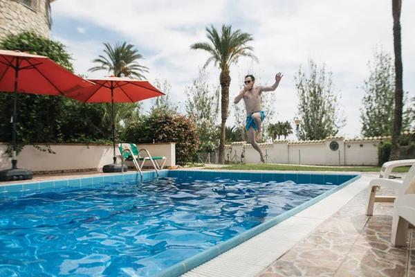 man having fun, jumping into the pool