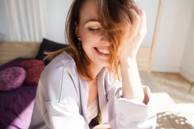 Güzel genç bir kadın gülümsüyor ve yatakta eğleniyor.