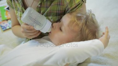 Anne bebek oğlu bir şişeden beslenir.