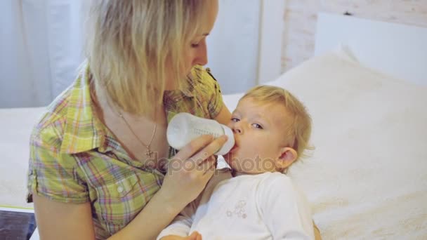 Anne bebek oğlu bir şişeden beslenir. — Stok video