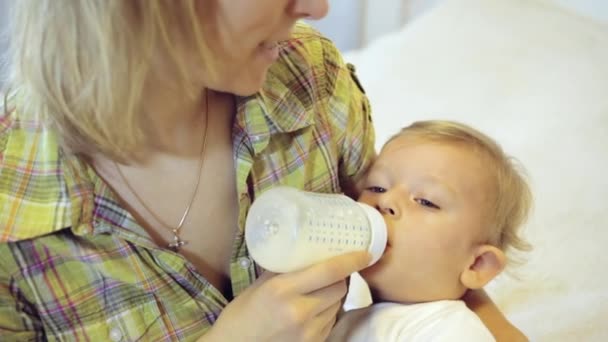 Mother feeds her baby boy from a bottle — Stock Video