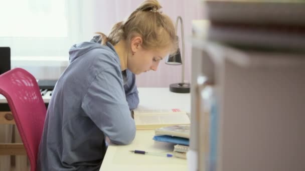 Teen girl doing her homework reading a geometry textbook — Stock Video