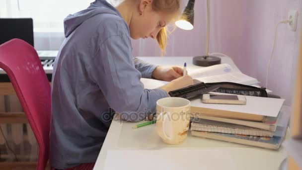 Teen girl doing her homework writing pen in a notebook — Stock Video