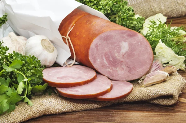 Pork sausage sliced in small pieces in a white packing on wooden — Stock Photo, Image