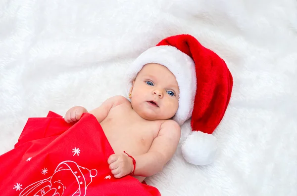 Five month old baby girl on the bed wearing a Santa hat — Φωτογραφία Αρχείου