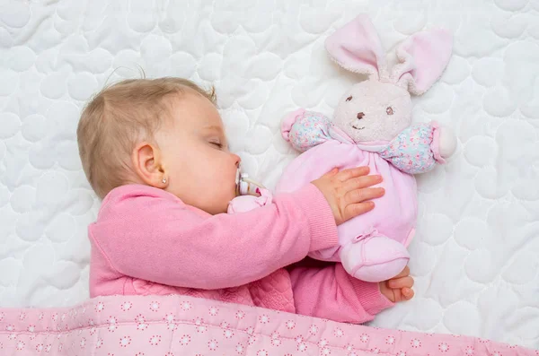 Meisje van de baby baby slapen op bed met zijn speelgoed paashaas — Stockfoto
