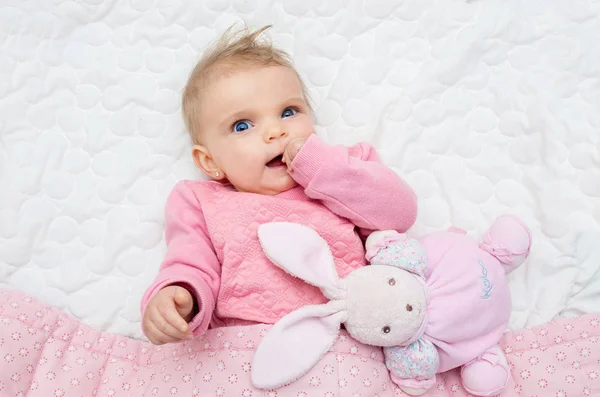 Happy baby babymeisje glimlachend op bed met zijn speelgoed paashaas — Stockfoto