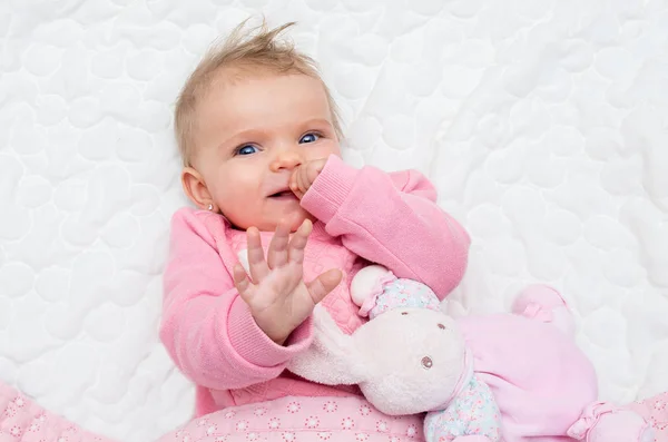 Bebê bebê menina feliz sorrindo na cama com seu coelho de brinquedo — Fotografia de Stock