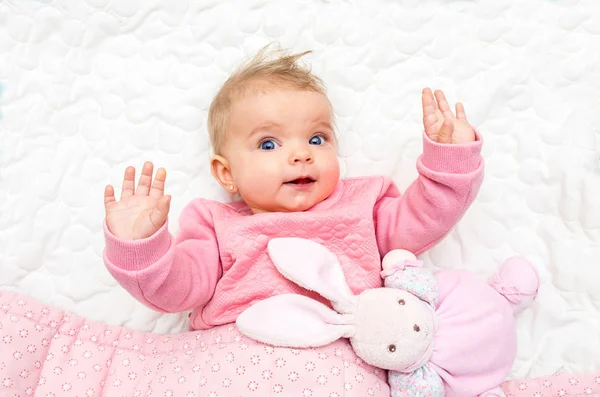 Happy baby babymeisje glimlachend op bed met zijn speelgoed paashaas — Stockfoto