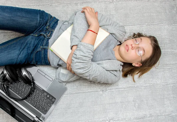 Chica adolescente durmiendo en el suelo con un libro en sus manos —  Fotos de Stock