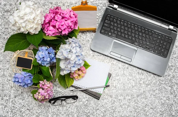 Lugar de trabajo con portátil, gafas, cuaderno, hermosas flores —  Fotos de Stock