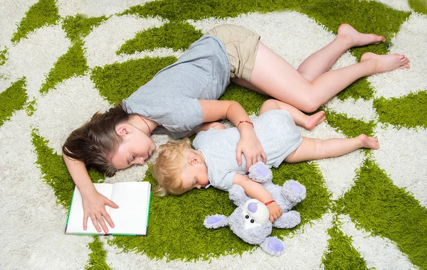 Moe twee meisjes zus viel in slaap op het tapijt — Stockfoto