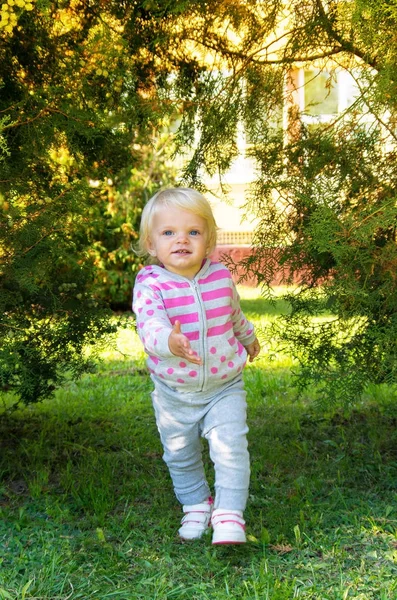 Adorable happy baby girl with blond hair walking in the park — Stock Photo, Image