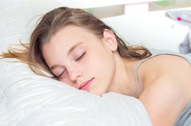 Güzel genç kız yatakta uyuyor. Portre.