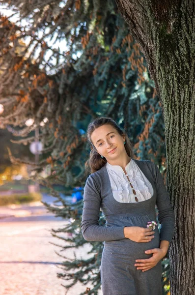 Hermosa joven feliz embarazada que se aloja en el parque de otoño —  Fotos de Stock