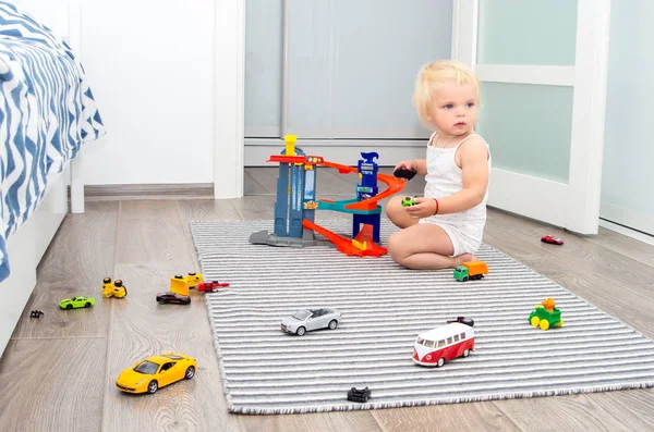 Loira bebê menina jogar brinquedo carros em casa — Fotografia de Stock