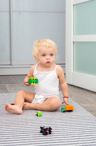 Loira bebê menina jogar brinquedo carros em casa — Fotografia de Stock